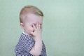 Defocused funny, happy child smiles and covers his face with his hand. The little child is embarrassed. Copy space -