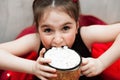 Defocused Funny little Girl Holding Cup with Hot Tasty Chocolate and Marshmellow and trying to eat it on cozy Red