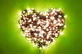 Defocused garland with lights folded in the shape of a heart on a green background Royalty Free Stock Photo