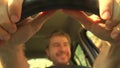 Defocused happy man putting his hands on leather steering wheel of the car