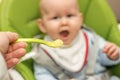 Defocused iimage of fathers hand feeding little baby boy with first solid food. Giving a spoon with baby puree Royalty Free Stock Photo