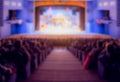 Defocused image. Auditorium in the theater during the performance. The scenery on the stage. Adults and children