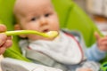 Defocused image of hand feeding little baby boy with first solid food. Giving a spoon with baby puree Royalty Free Stock Photo