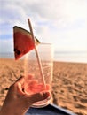 Defocused image of handholds an empty glass of watermelon juice on beach background