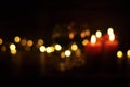 Defocused light from garlands and candles. Burning candles in the dark. The concept of Christmas and New Year comfort