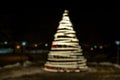 Defocused lights spiral Christmas tree with bokeh on dark background.