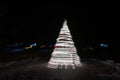 Defocused lights spiral Christmas tree with bokeh on dark background.