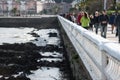 Defocused people strolling along promenade and waves crashing on rocks