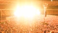 Defocused photo of people listening and watching big rock concert on music festival at big stadium. Crowd of fans