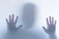 Defocused scary ghost silhouette behind a white glass background