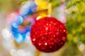 Defocused shining red Christmas ball hanging on branch of Xmas pine tree. Colorful creative abstract blurred bokeh Royalty Free Stock Photo