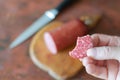 A defocused shot of a hand holding a piece of salami over the ki