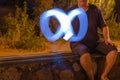 Defocused shot of man drawing blue light sign of infinity in nig Royalty Free Stock Photo