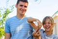 Defocused smiling preteen caucasian girl playing with finger young caucasian man. Summer outdoor blue sky and green tree