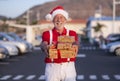 Defocused smiling senior bearded man shopping for Christmas in a Santa hat and suspenders, holding gifts and looking at camera