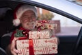 Defocused smiling senior man inside his car wearing a Santa hat ready to home delivery of Christmas gifts. An old bearded