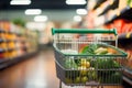 Defocused supermarket aisle as a backdrop for an empty green cart