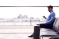Defocused View Of Businessman Sitting In Airport Departure Lounge Using Mobile Phone