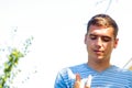 Defocused young caucasian man looking at his finger. Summer outdoor background. Out of focus