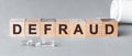 Defraud is a word written in black letters on wooden cubes Royalty Free Stock Photo