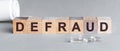 Defraud is a word written in black letters on wooden cubes