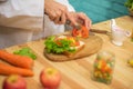 With deft professional the chef in close up shot sliced through the juicy tomato on the cutting board in a kitchen.