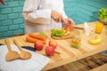 With deft professional the chef sliced through the juicy tomato on the cutting board in a kitchen full of cooking ingredients and