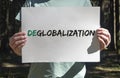 Deglobalization and reverse globalization concept. Word on paper placard in male hands with forest background Royalty Free Stock Photo