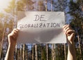 Deglobalization and reverse globalization concept. Word on paper poster in male hands with forest background Royalty Free Stock Photo