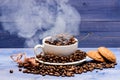 Degree of roasting grain. Cup full coffee brown roasted beans white clouds of smoke blue wooden background. Cafe drinks Royalty Free Stock Photo