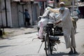 An old man pulls his rickshaw wearing face mask.