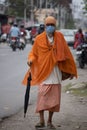A Sadhu wearing mask going on the road.