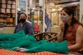 Two Beautiful ladies shopping for a saree in a store, wearing face mask in Corona epidemic in India.