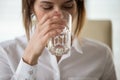 Dehydrated female office worker drinking still mineral water Royalty Free Stock Photo