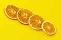 Dehydrated slices of dried oranges diagonally against a bright yellow background. Healthy food concept, vitamins, aromatherapy and