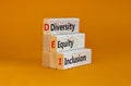 Diversity, equity, inclusion symbol. Wooden blocks with words DEI, diversity, equity, inclusion on beautiful orange