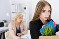 Dejected fired office worker carrying a box full of belongings