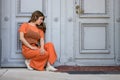 Dejected woman crouching against a historic wooden door waiting