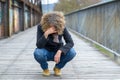 Dejected woman squatting on a bridge