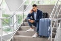 Delayed Flight. Worried Man Sitting On Stairs In Airport, Talking On Cellphone Royalty Free Stock Photo