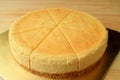 Delectable fresh baked creamy yellow whole plain cheesecake isolated on wooden table