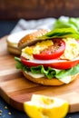 Homemade bagel with scramble egg bacon cheese tomato and lettuce on a board generated by ai Royalty Free Stock Photo