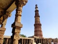 Tall ancient minaret representing hidden glorious past of India at Qutub Minar and Jain temple ruins.