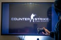 Man holding a steam controller and playing popular video game counter strike on a television and PC