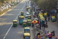 Indian urban traffic and green yellow rickshaws taxi parking near pedestrians and street trading,