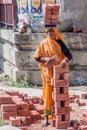 DELHI, INDIA - OCTOBER 22, 2016: Female worker carrying a load of bricks on her head in the center of Delhi, Indi