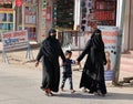 Veiled women and black jacket are shopping at the market.