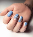 Delicate blue gel polish with a beautiful design of twigs. A woman`s hand with a professional manicure.