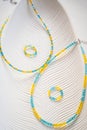 Delicate blue and yellow beaded necklace on textured white surface Royalty Free Stock Photo