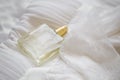 Delicate bride perfume on white lace and silk bride dress, transparent bottle perfume selective focus